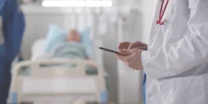 Arzt in Patientenzimmer mit Smartphone