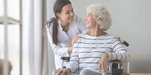 Weibliche Palliativpatientin im Rollstuhl mit Pflegekraft